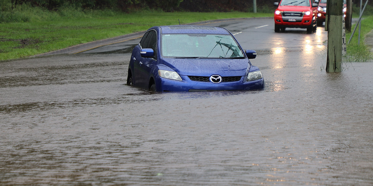 Blue car stuck and flooded in water.