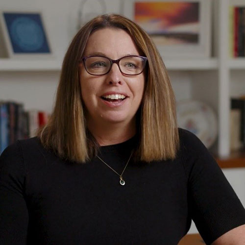 A woman named Michelle. She is smiling and wearing a black top and black glasses.