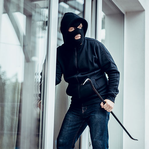 A thief wearing balaclava breaking into a house