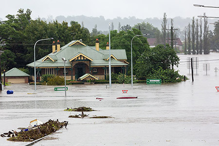 Severely flooded street with partially submerged house and road signs