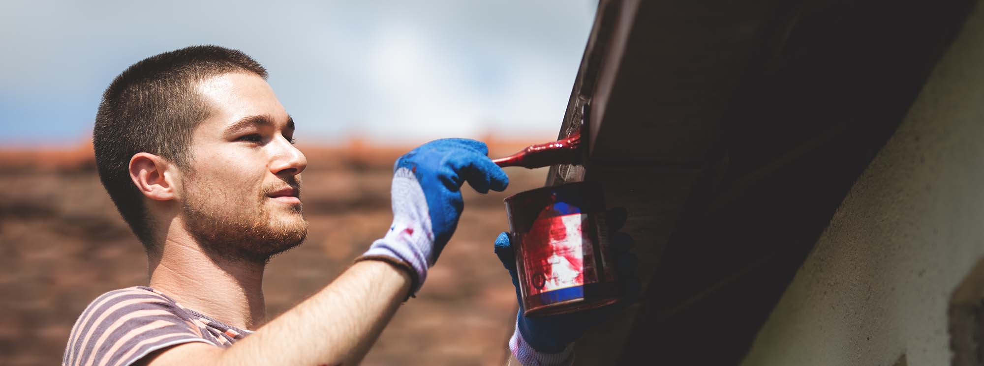 A man painting a roof gutter